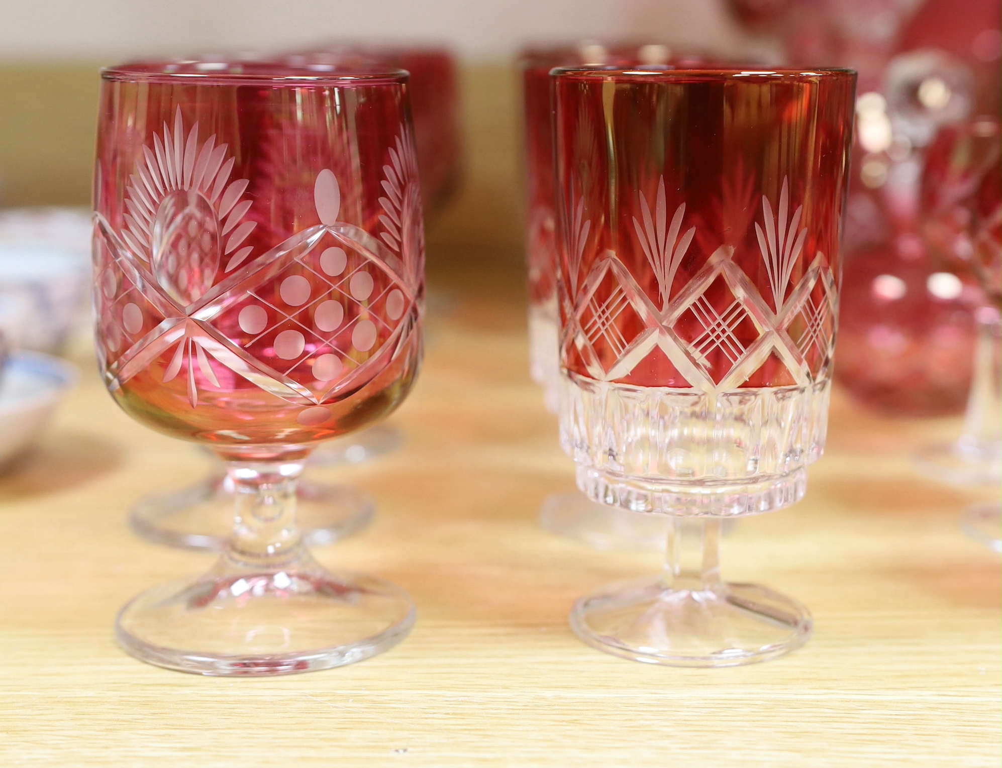 Cranberry glassware including a pair of cut glass decanters, together with a smaller pair and various suites of similar wine glasses, the largest 33cm high